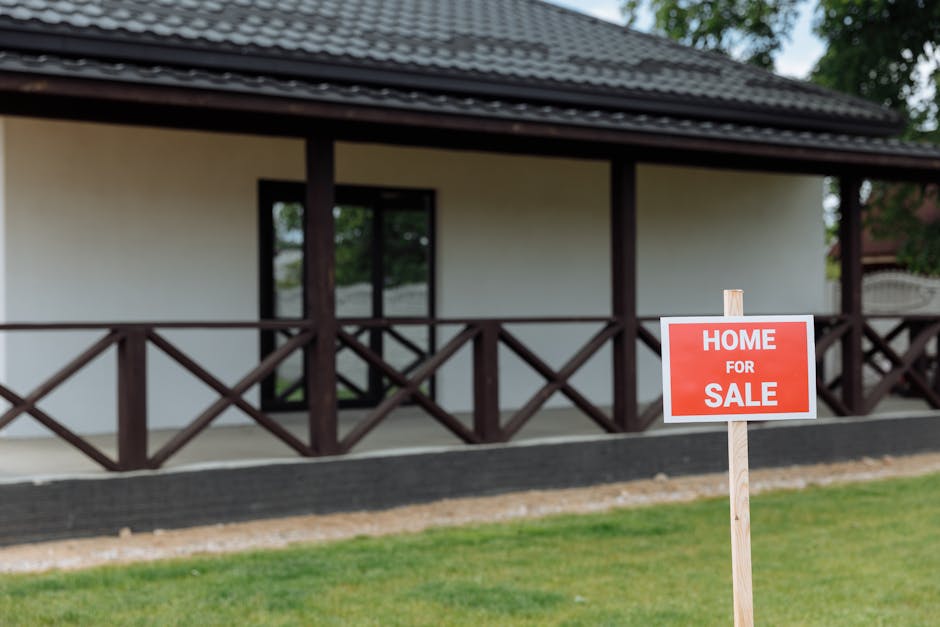 White house with porch and 'Home for Sale' sign on a sunny day
